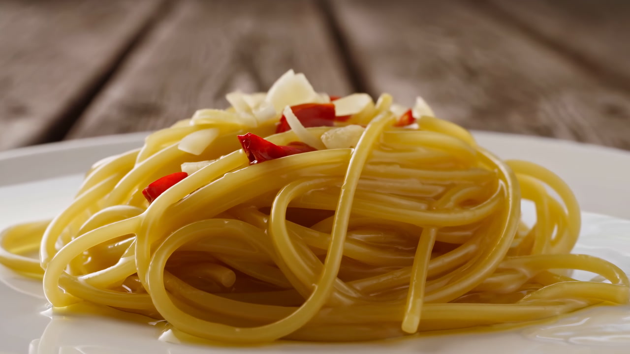 Closeup Spaghetti Garlic Chili White Plate On Rustic Wood Table, Olive Oil Drizzle, Shaved Parmesan, Warm
