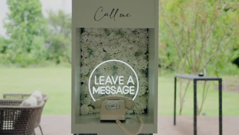 decorative phone booth with a "leave a message" sign, floral backdrop, and outdoor setting