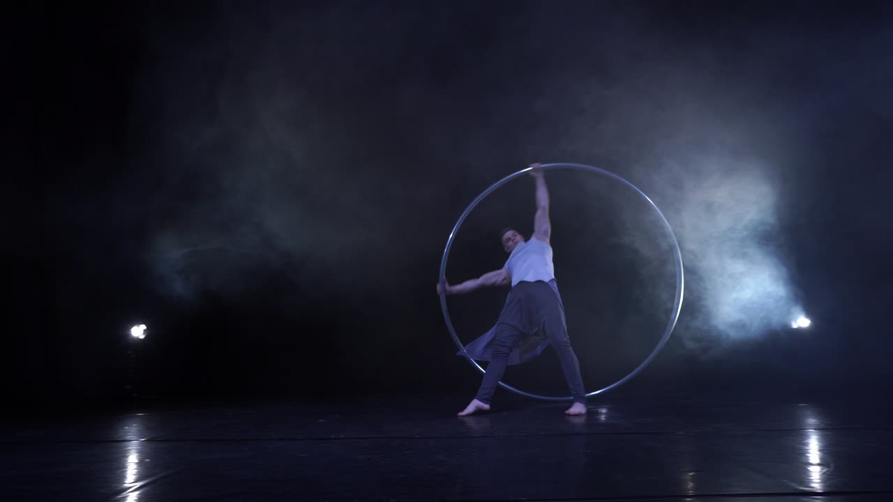 Artista circense mostra concentrazione ed equilibrio mentre gira su una ruota Cyr