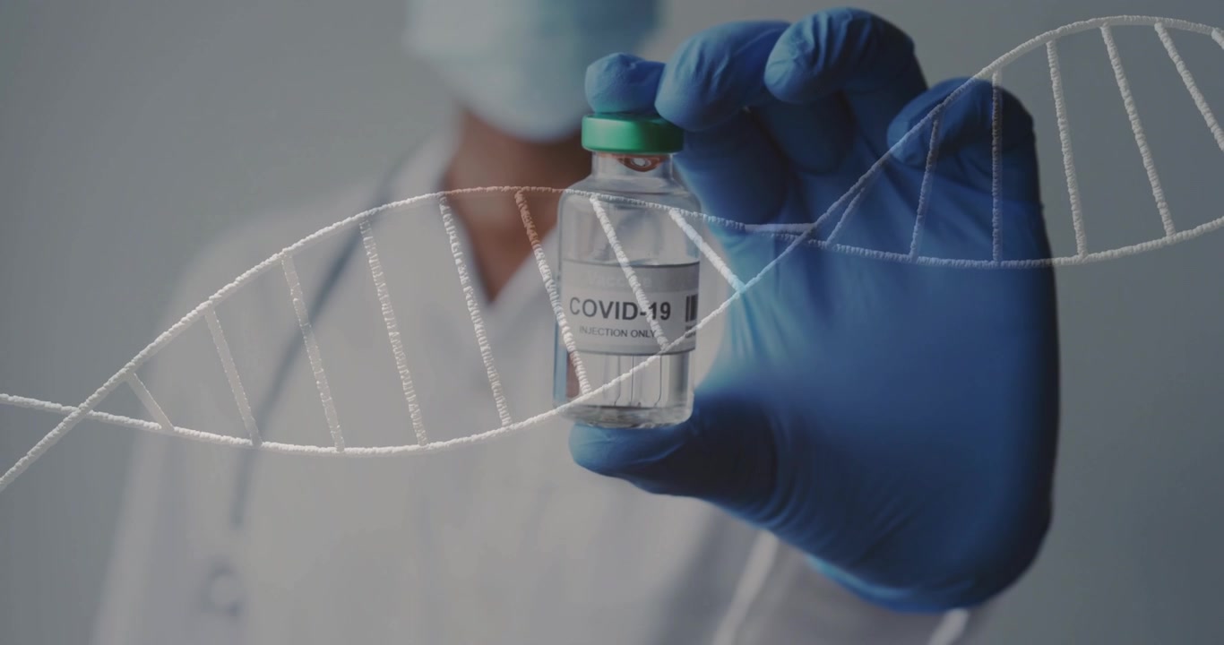 Reaching gloved-hand, nurse in studio with coat raising COVID-19 vial to show label with DNA helix