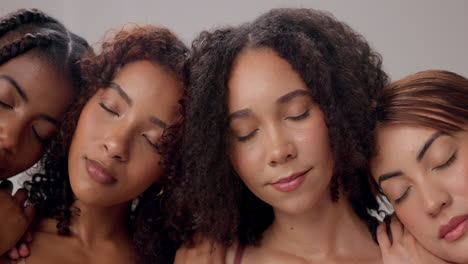 four women with their eyes closed, smiling together