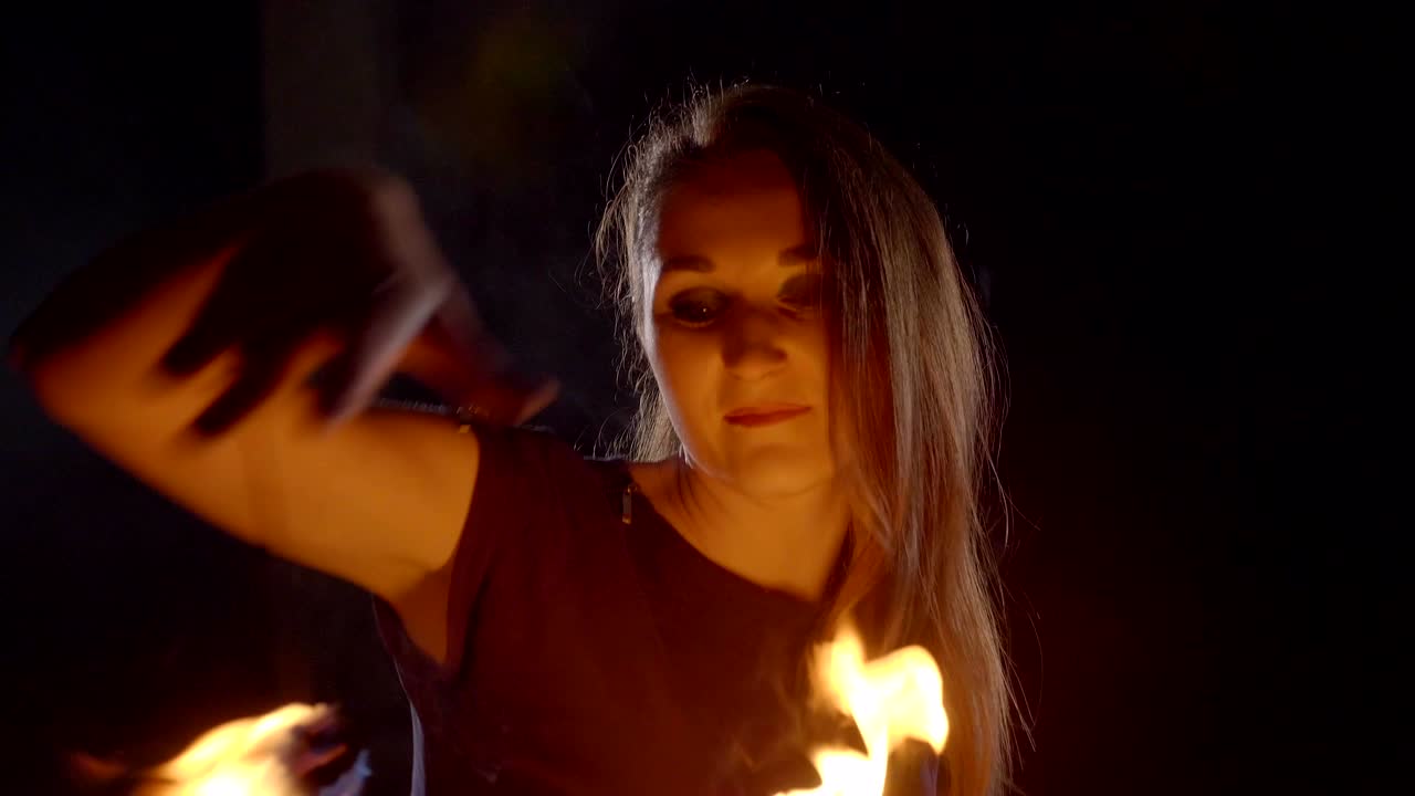 una artista de yong hace un espectáculo de fuego en la oscuridad a cámara lenta.