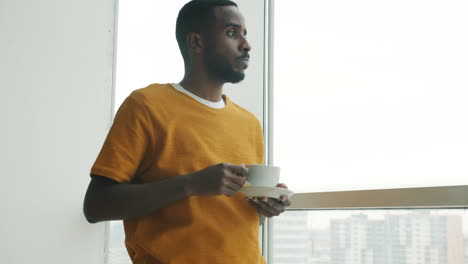 man drinking coffee by the window