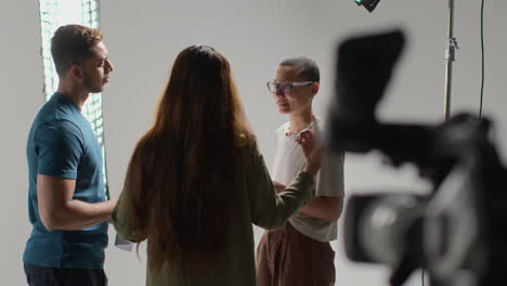 film director talking with male and female actors holding scripts rehearsing for shooting movie or video in studio