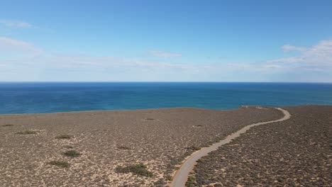 Antena-De-Drones-Sobre-Una-Carretera-Sinuosa-Con-Vistas-Al-Agua-Azul-En-Un-Día-Soleado