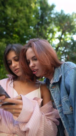 two young women looking at a phone outdoors