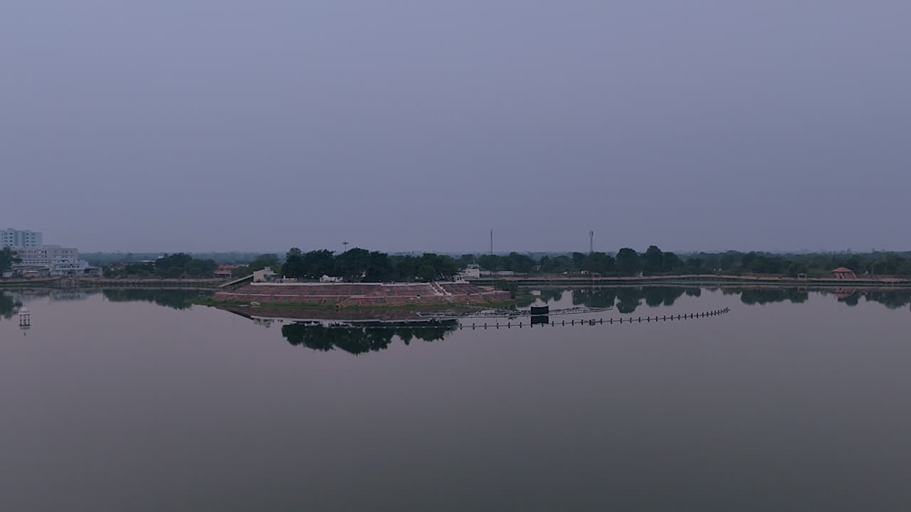 Sharmishtha Lake, Vadnagar, Gujarat, India con riflessi di acqua calma, skyline della città e cielo serale che creano un'atmosfera rilassante per temi quali viaggi, ambiente, meditazione e natura urbana