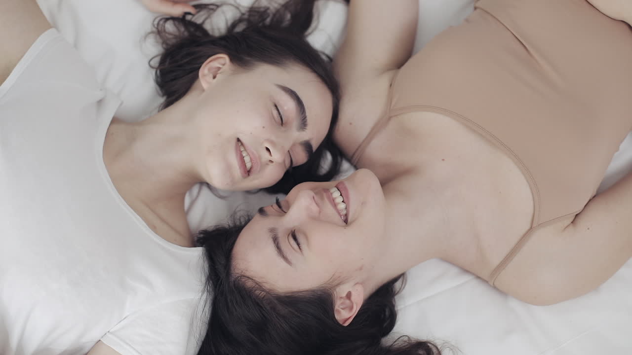Due donne sdraiate a letto che sorridono
