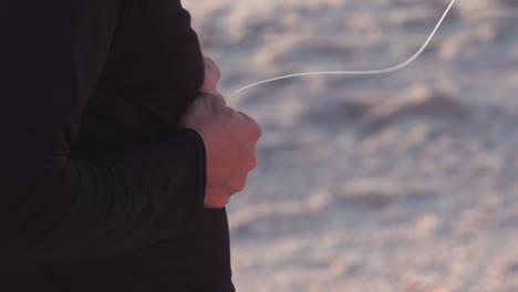 어부는 하얀 모래 해변에서 낚싯줄을 준비합니다