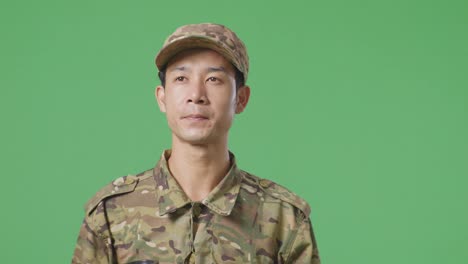 un soldado asiático caminando y bebiendo café en el estudio de fondo de la pantalla verde