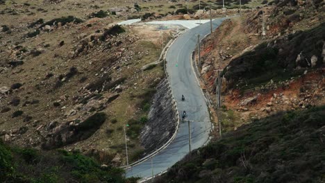 Three-motorbikes-drive-scenic-road-in-mountains-in-Ninh-Thuan-province,-Vietnam