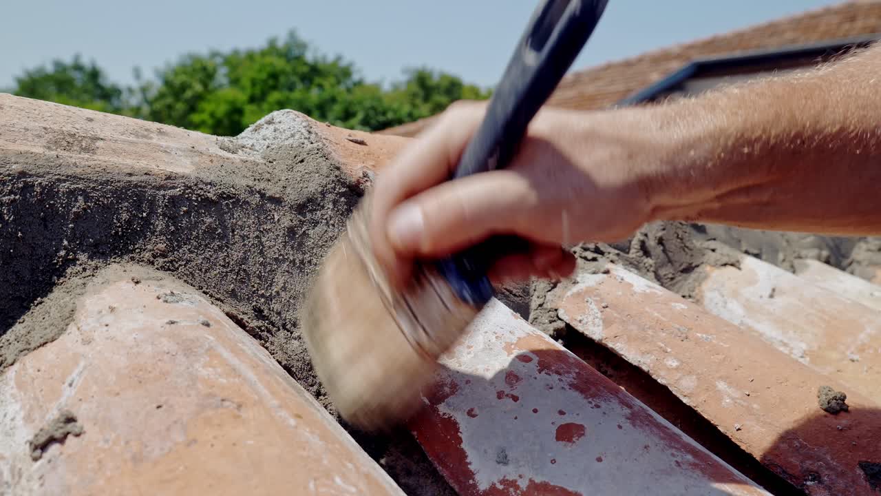 Man hand brushes wet cement from terracotta tiled wall close up slow mo
