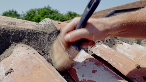 el hombre cepilla con la mano el cemento húmedo de la pared de baldosas de terracota de cerca en movimiento lento