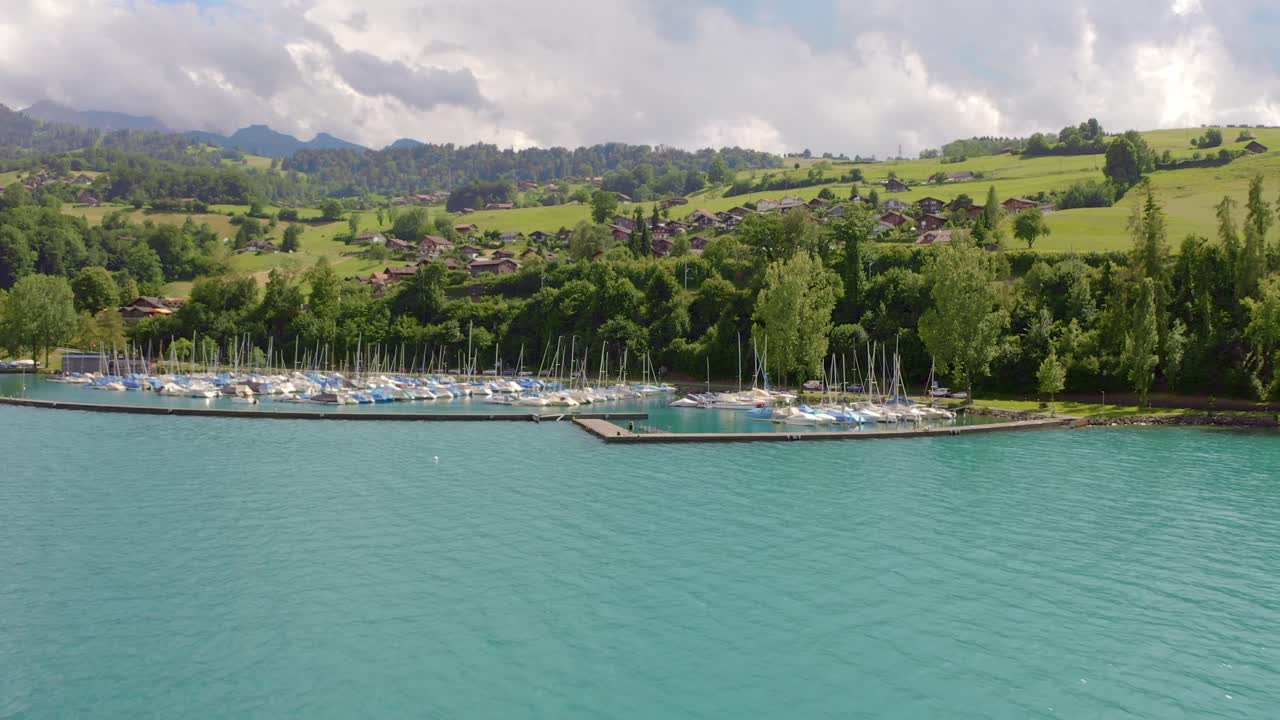 범선이 많은 작은 항구를 향해 멋진 맑은 푸른 물 위를 날아갑니다.