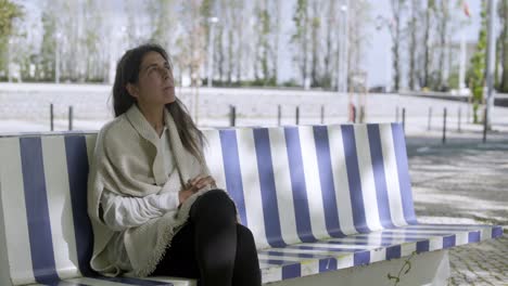 Tired-middle-aged-woman-sitting-on-bench-and-looking-at-sky