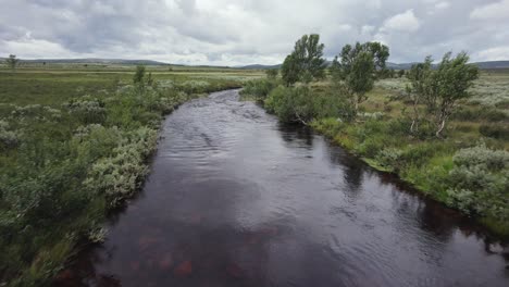 Aerial-swoops-over-small-bridge-to-follow-natural-river,-Spekdalen-NOR