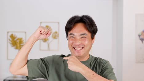 a man in a green shirt expresses excitement and triumph in a well-lit room with decorative wall art