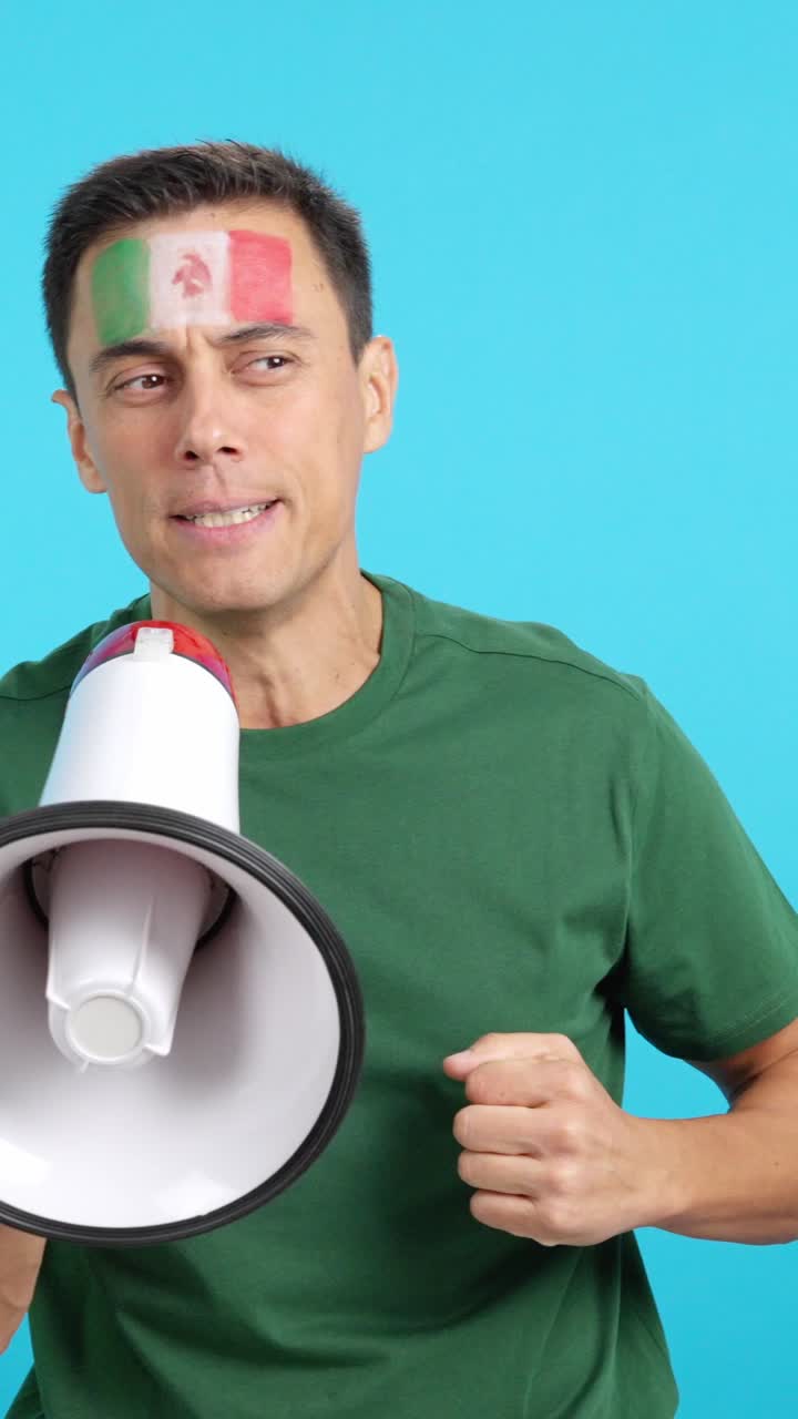 Excited man with mexican flag on face using a megaphone