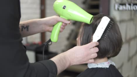 mujer joven se viste el cabello en una peluquería. un peluquero masculino se está secando el cabello con un secador de cabello. filmado en 4k