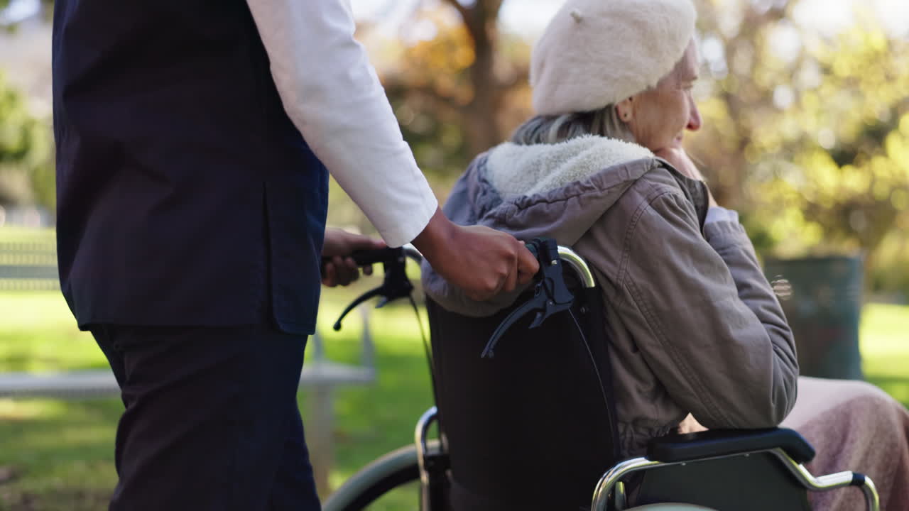 Elderly woman in wheelchair with caregiver outdoors