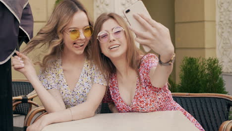 two young women friends taking a selfie at a cafe