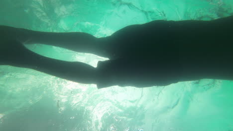 man swimming in pool under coconut tree resort hotel under water shot slow motion