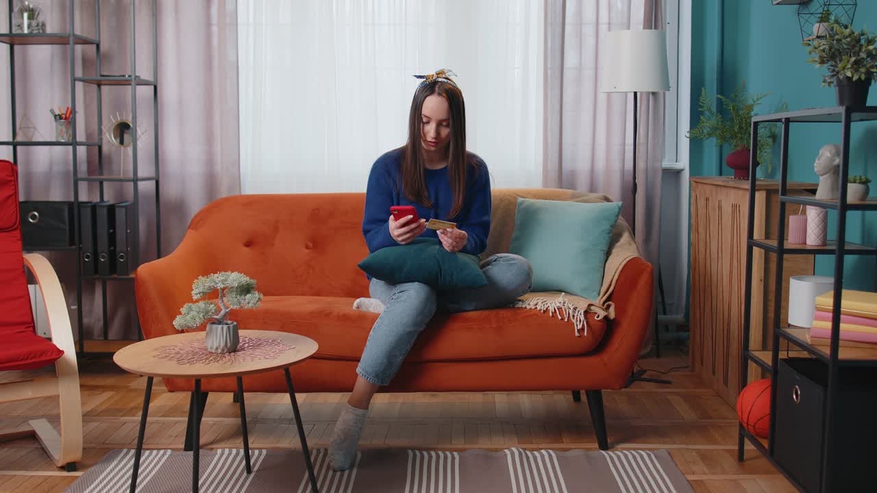 mujer sentada en casa usando tarjeta de crédito bancaria y teléfono inteligente mientras transfiere dinero a compras en línea