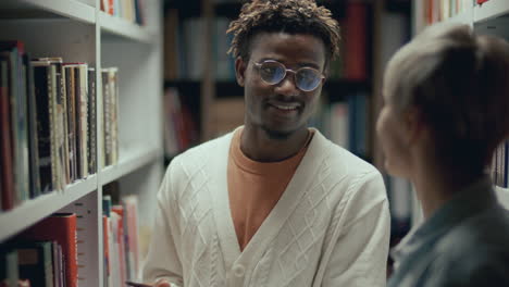 estudiante afroamericano hablando con un amigo en la biblioteca de la universidad