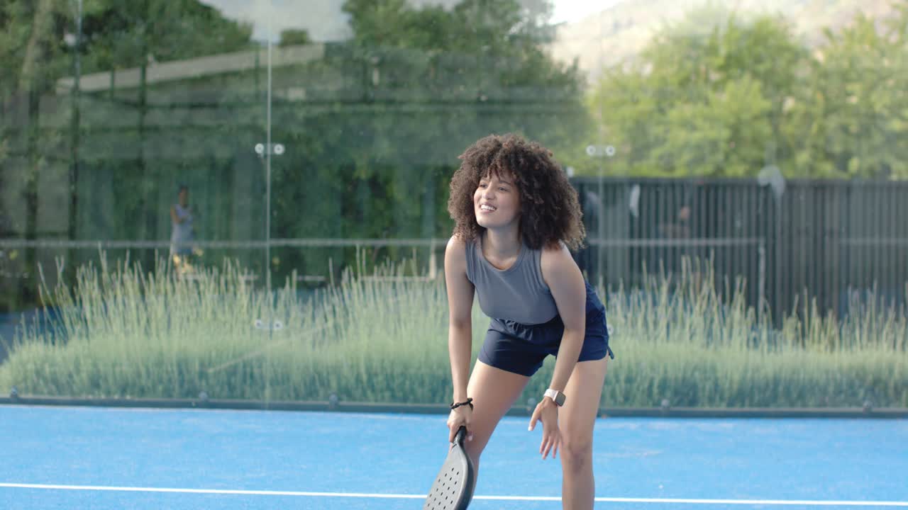 African American woman expecting shot, adjusting paddle grip, preparing return on blue court