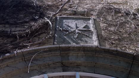 historical emblem above castle entrance with dead branches