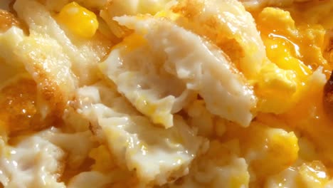 un primer plano de huevos revueltos después de ser cortados con tenedor y cuchillo.