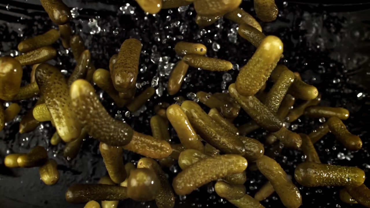Super ralenti de cornichons éclaboussant l'eau.