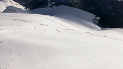 AERIAL---People-skiing-in-mountains-at-Kolasin-ski-resort,-Montenegro,-pan-right