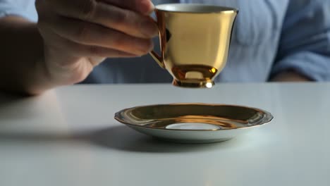 man waiter serving woman customer coffee from golden espresso cup, woman drinking coffee, close up