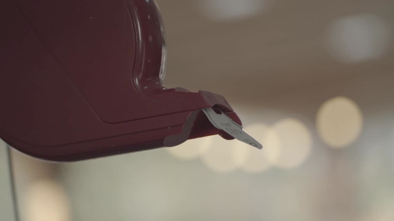 Primo piano di una mano che prende un biglietto da un distributore rosso, semplicità ed efficienza della gestione delle code.