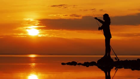 mujer pescando en una caña de pescar girando en el fondo del atardecer.
