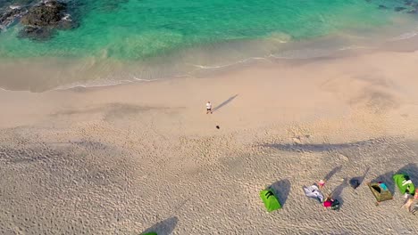 a drone ascends away from a man on a beach before the shot morphs into a dramatic special effect