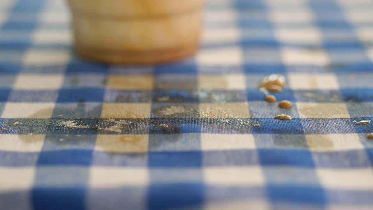 Cup and Spilled Liquid on Checkered Tablecloth