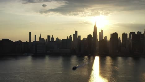 a dolly shot moving forward towards new york city - a golden sunset, looking down at the river as a ferry moves towards the drone camera