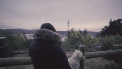 HD-of-a-woman-and-her-dog-outdoog-house-in-front-of-a-lake