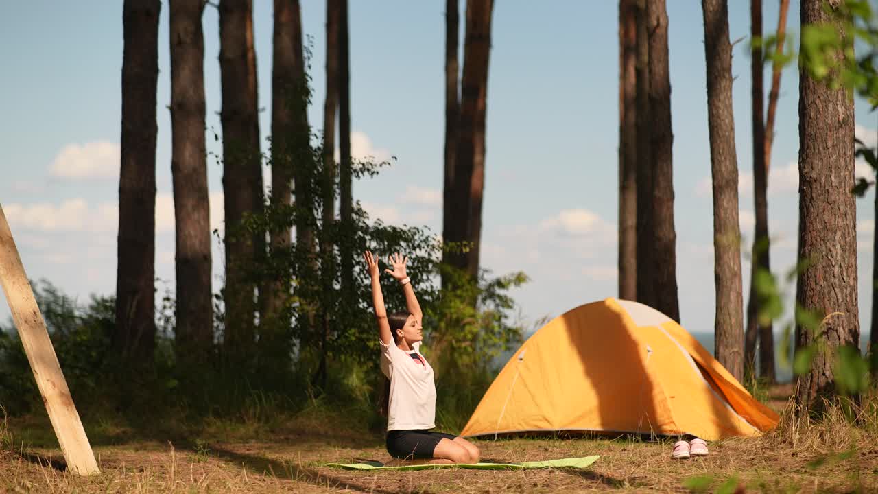 텐트 근처 의 숲 에서 요가 를 연습 하는 여자