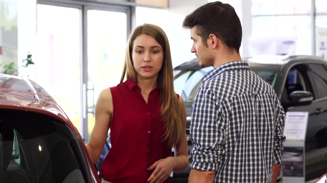 joven hermosa hablando con su hombre en el concesionario