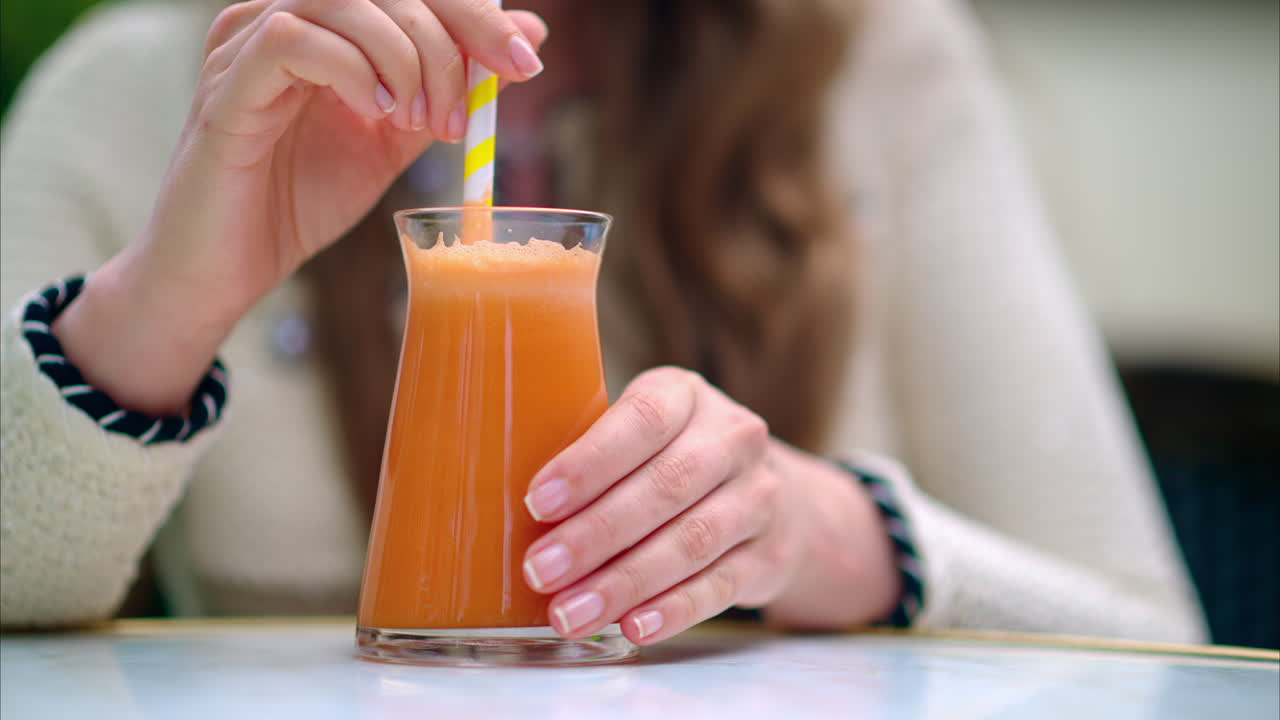 Woman drinking an orange juice using of a straw, at a cafe, outside