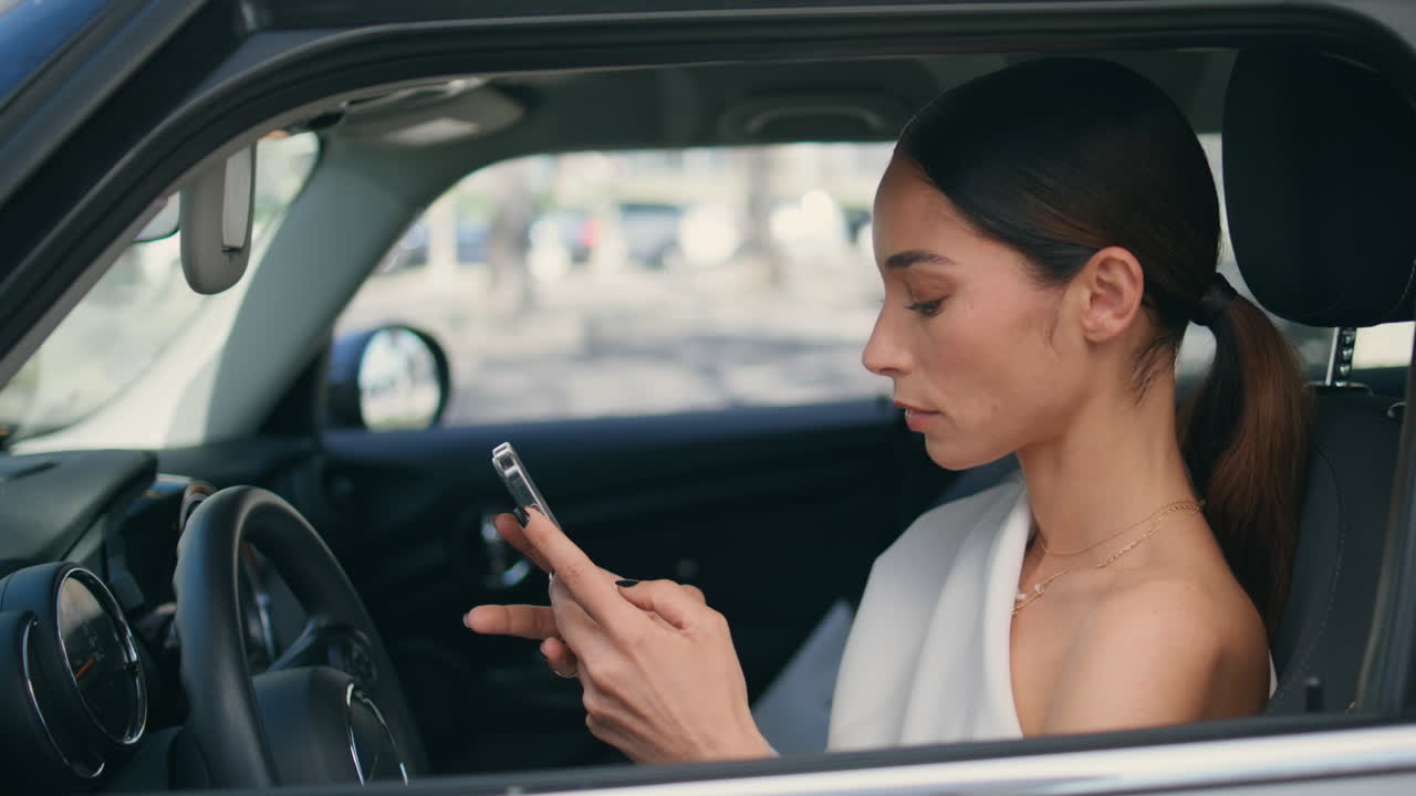mujer conductor mirando la pantalla del teléfono sentada cerca de la rueda del coche. dama con teléfono
