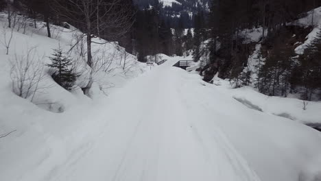 drone flying backwards over trail in a snowy valley in the alps, kleinwalsertal,austria