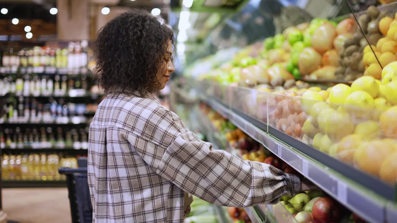 mujer sonriente eligiendo frutas frescas en el supermercado en una bolsa de papel