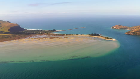 aerial view of a coastal estuary with sandbar and pier