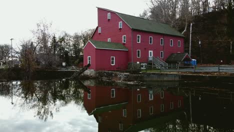 drone flies towards a red mill near the water