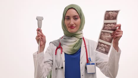 female doctor in hijab holding ultrasound transducer and sonogram