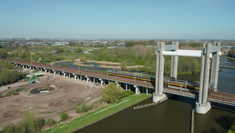 ns intercity train traveling through railway bridge over the canal at summer in gouda, netherlands